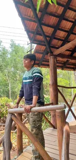 Person enjoying nature on rustic cabin porch with forest backdrop.