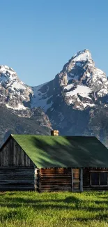 Rustic cabin with mountains in the background under a clear blue sky.