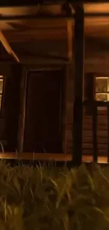 Rustic wooden cabin at night with warm lighting and grassy foreground.