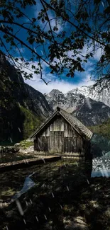 Rustic cabin by a mountain lake with trees and clear blue sky.