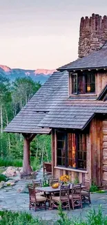 Rustic cabin in forested mountain landscape with outdoor seating.