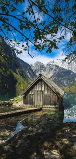 Rustic cabin by a serene mountain lake under blue skies.