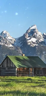 Rustic cabin with snow-capped mountain view and green meadow.