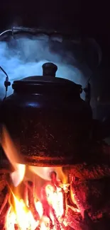 Rustic kettle over campfire at night.