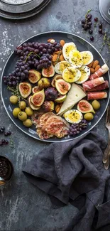A rustic charcuterie board with figs, grapes, and cheese on a gray background.