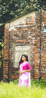 Woman in traditional attire by rustic red brick house.