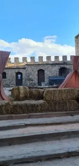Rustic fort with hay bales and tents under a blue sky.