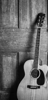 Black and white acoustic guitar against a wooden door.