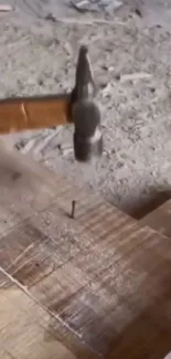 Hammer driving nail into wooden surface