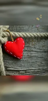 Rustic red heart against wooden texture with rope.