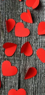 Red paper hearts on rustic wood background for mobile wallpaper.