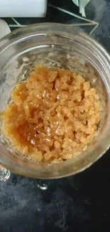 Golden honeycomb texture in a glass jar on a dark surface.