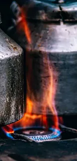 Twin rustic metal kettles on a stove with vibrant flames.