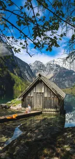 Rustic cabin by a tranquil mountain lake with clear blue sky.