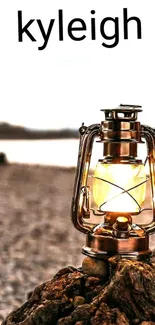 Rustic lantern illuminated on a rocky beach.