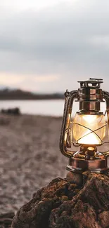 Rustic lantern on a sandy beach at dusk with soft glow.