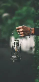 Hand holding a lantern against green foliage background.