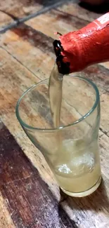 Drink pouring into a glass on a wooden table.