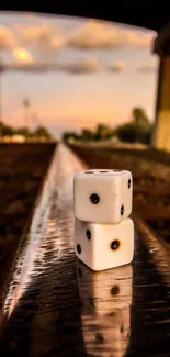 Stacked dice on a railroad track at sunset.