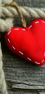 Red fabric heart on rustic wooden background with rope.