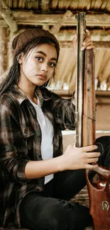 Young woman in rustic setting with vintage rifle, sitting against a wooden backdrop.