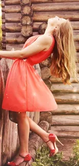 Woman in coral dress by rustic wooden fence.