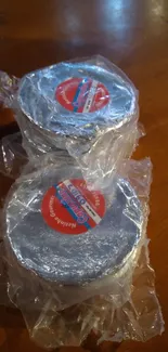 Silver objects wrapped in plastic on a wooden surface.