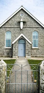 Rustic stone church with blue door and arched windows, surrounded by greenery.