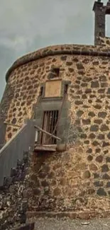 Rustic stone tower with intricate architecture against cloudy sky.