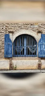 Rustic stone wall with blue shutters and arched window.