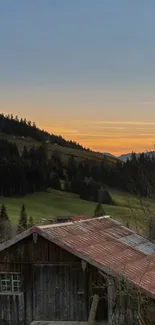 Tranquil sunset over rustic cabin in lush green valley with clear blue sky.