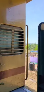 View through a rustic train door with vibrant blue sky.