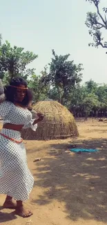 Woman in polka-dot dress in rustic village setting.