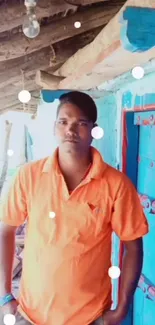 Man in orange shirt by a blue rustic door.