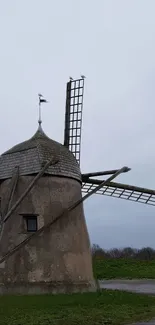 Rustic windmill against a cloudy sky in a serene landscape.