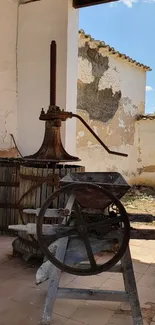 Vintage wine press with rustic stone building.