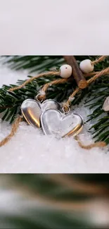 Heart charms on snowy pine branch with rustic winter theme.