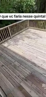 Wooden deck with railing surrounded by trees.