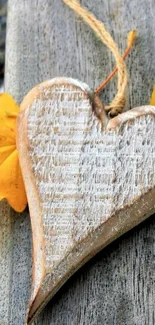 Rustic wooden heart with autumn leaves on timber background.