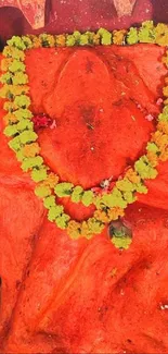 Vibrant red idol with a floral garland in sacred surroundings.