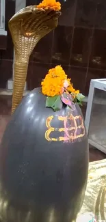 Sacred Shivling decorated with orange flowers and a golden background.