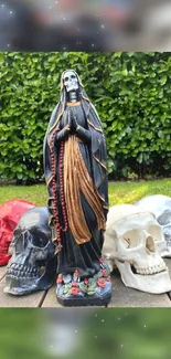 Dark-robed statue with colorful skulls on a wooden surface and green background.