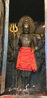 Sacred stone statue with intricate carvings and a vibrant red cloth.