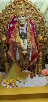 Golden Sai Baba statue with flowers and intricate decor, perfect for wallpaper.