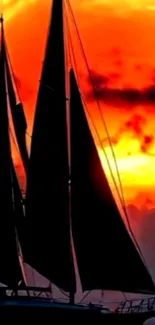 Silhouetted sailboat against fiery sunset sky.