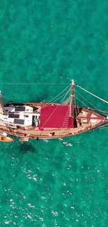 Aerial view of a sailboat in turquoise waters, offering a serene and adventurous vibe.