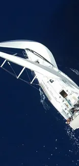 Aerial view of a sailing yacht on dark blue ocean waters.