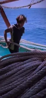 Sailor on a wooden boat with ropes on the blue ocean.