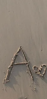 Letter A drawn in sand with a heart on a beach background.