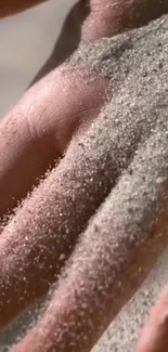 Closeup of a hand covered with fine sand.